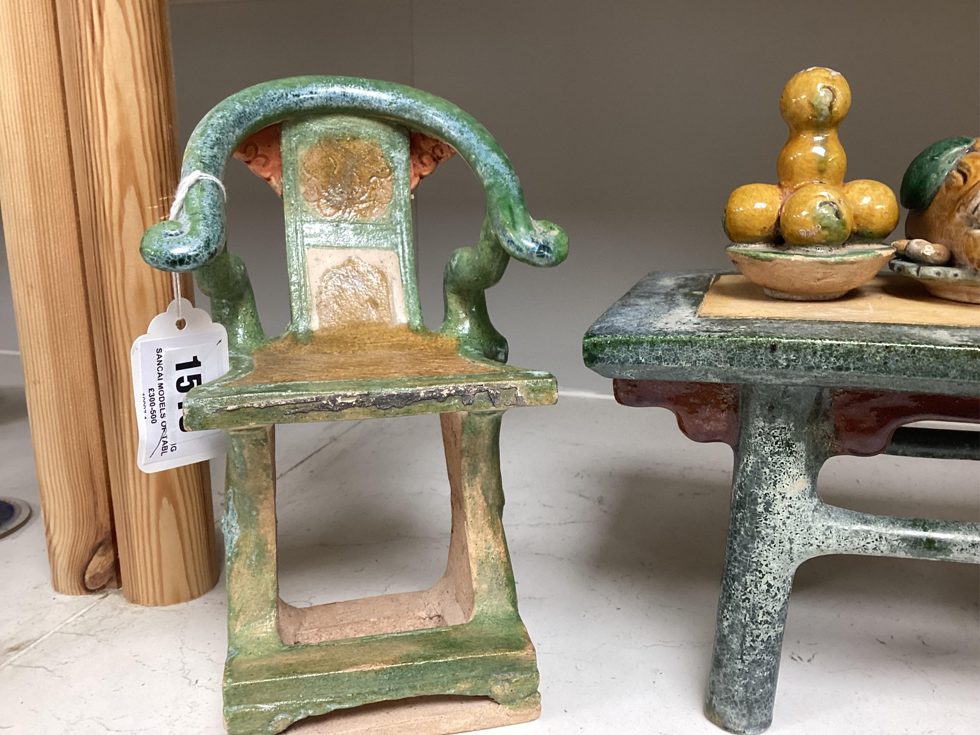 A set of Chinese Ming Sancai models of table with offerings and a pair of horseshoe shaped armchairs, 16th century, the chairs each 22cm high